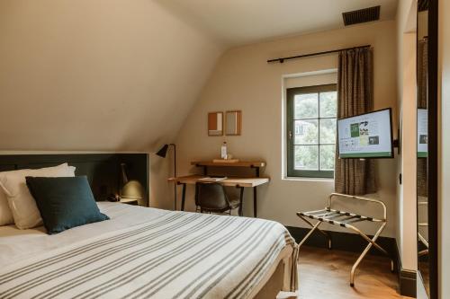 圣马尔滕斯·拉特姆杜普切旅馆的一间卧室配有一张床、一个窗口和一张书桌