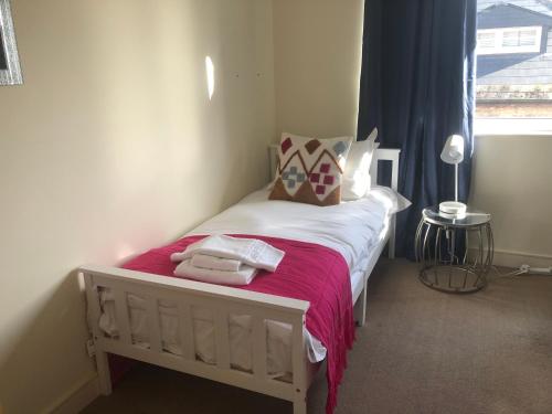 切尔滕纳姆Luxury Town Centre Property with parking的一间卧室配有一张带粉色床单的床和一扇窗户。