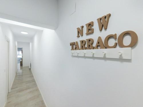 塔拉戈纳Apartamento New Tarraco的墙上有新的格子花标志的白色走廊