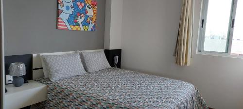 若昂佩索阿Flat à beira mar, charmoso e aconchegante的一间卧室配有一张带床罩的床和窗户