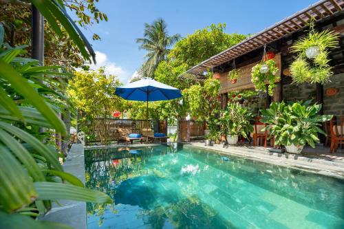 会安Sands River Hoi An Villa的一座房子旁带遮阳伞的游泳池