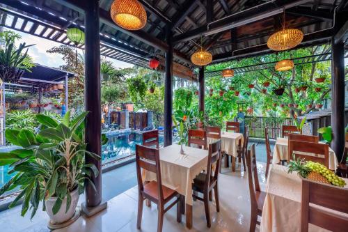 会安Sands River Hoi An Villa的一间设有桌椅的餐厅,种植了植物