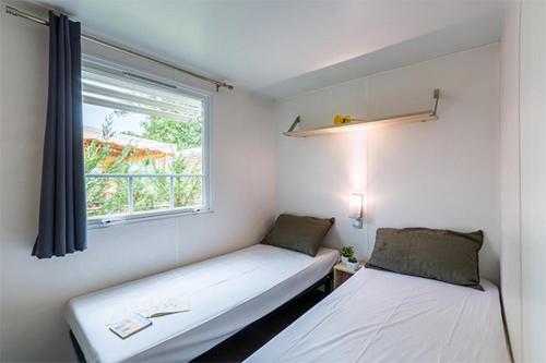 莱马特CAMPING LA PINEDE的小房间设有两张床和窗户