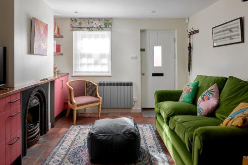 法纳姆Pearls Cottage的客厅设有绿色沙发和壁炉