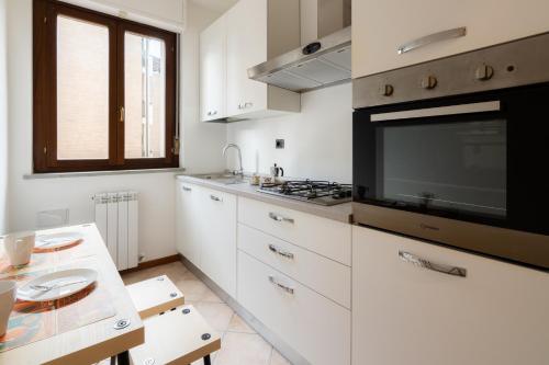 福利尼奥MIZAR- Appartamento privato con parcheggio gratuito by Appartamenti Petrucci的厨房配有白色橱柜和平面电视。