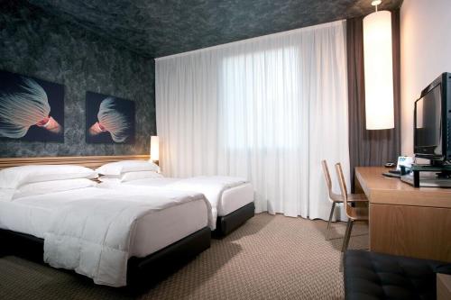 瓦多利古雷Sea Art Hotel的酒店客房配有一张床、一张书桌和一台电视。