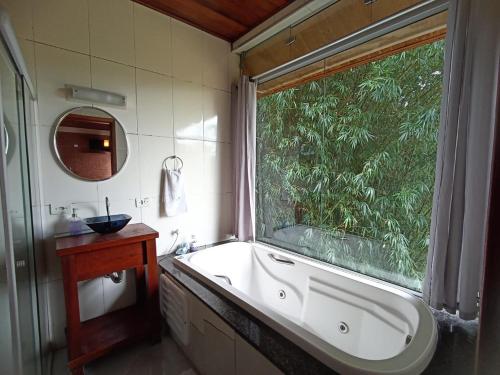 帕赖索波利斯Chalé Recanto do Sol的带浴缸的浴室和大窗户