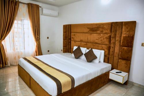 莱基247 Luxury Hotel & Apartment Ajah的一间卧室配有一张大床和木制床头板