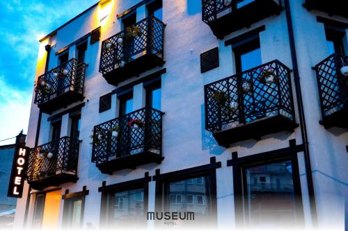 普里什蒂纳Museum Hotel的白色的建筑,设有黑色阳台和窗户