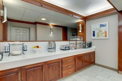 布朗伍德Best Western Plus Riata Hotel的一个带木制橱柜和白色台面的大厨房