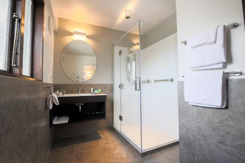 基督城Scenic Hotel Cotswold的带淋浴、盥洗盆和镜子的浴室