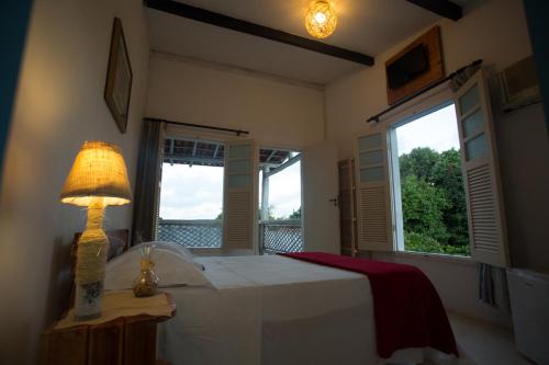 伊塔乌纳斯伊塔乌纳斯维拉曼迪旅馆的一间卧室配有一张带灯的床和两个窗户