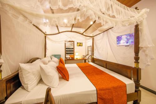 米瑞莎Mimoza Mirissa的一间卧室配有带橙色和白色枕头的天蓬床