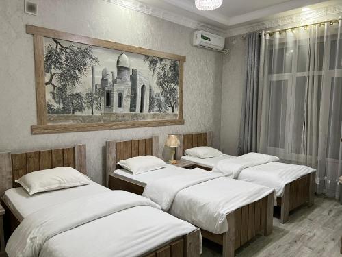 撒马尔罕理想酒店的墙上画画的房间的三张床