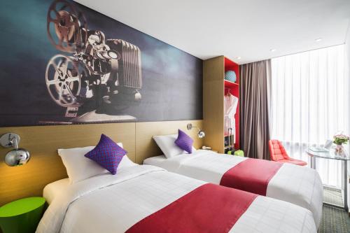 首尔ibis Styles Ambassador Seoul Myeong-dong的酒店客房设有两张床,墙上挂有绘画作品