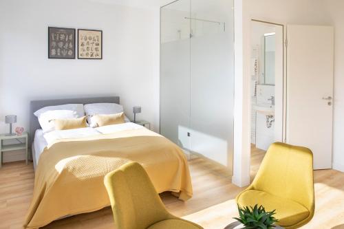 不莱梅Louis & Louise Apartments & Rooms I Digital Check In的一间卧室配有一张床和两张黄色椅子