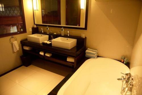 乌布Cinta inn的浴室设有2个水槽、浴缸和镜子