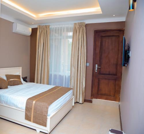 达累斯萨拉姆Hotel Amaranth的卧室配有床、电视和门