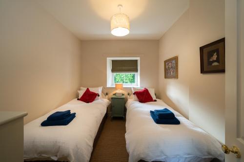 Riverside Cottage, Bridge of Balgie, Glenlyon, Perthshire的两张床铺,房间配有红色和蓝色枕头