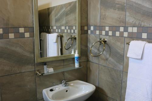 SimunyeLivivane Guest House的浴室配有盥洗盆、镜子和毛巾