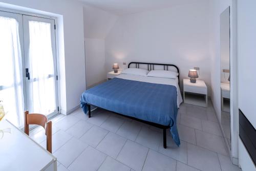 圣贝内代托-德尔特龙托Residence Dolcemare的白色卧室配有一张带蓝色毯子的床