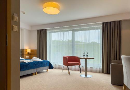 尤斯托尼莫斯基Hotel SKAL Medi SPA & Resort的酒店客房设有床、桌子和窗户。