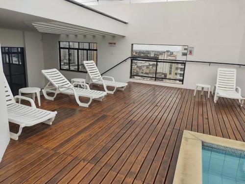 坎普斯戈伊塔卡济斯Apto acolhedor, confortável e bem localizado的一个带白色椅子的甲板和游泳池