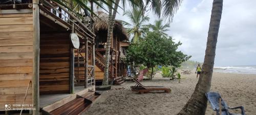圣玛尔塔HOSTAL Estrellas del tayrona playa的棕榈树海滩上的木制建筑