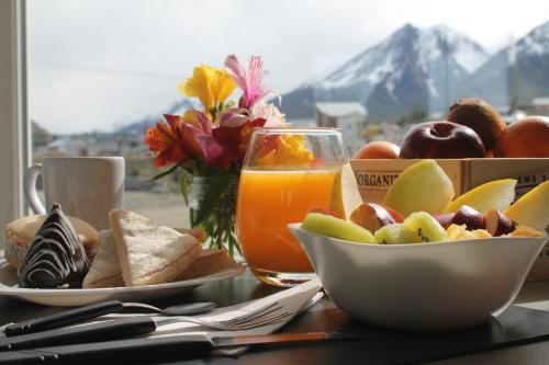 乌斯怀亚Comarca Fueguina的一张桌子,上面放着一碗水果和一杯橙汁