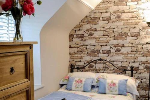 牛顿斯图尔特Woodbank Cottage Newton Stewart的一间卧室设有石墙和一张带枕头的床。