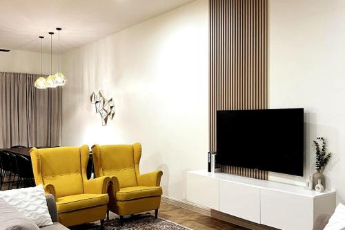 汝来Lapan Ompek Homestay 3 Bedrooms的客厅配有2把黄色椅子和电视