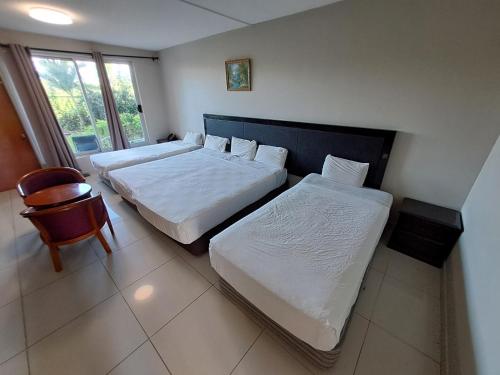 南迪Trans International Hotel的一间卧室设有两张床、一把椅子和一个窗户。