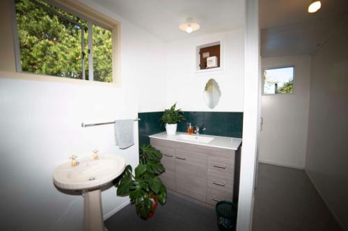 OwakaSurat Bay Lodge by the Sea/Backpackers Hostel的白色的浴室设有水槽和镜子