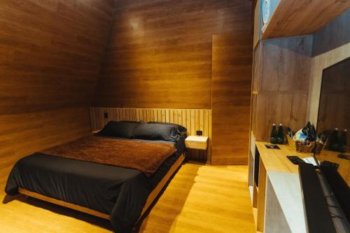 恩维加多Oculto refugio de bosque的卧室配有一张床铺,位于带木墙的房间内