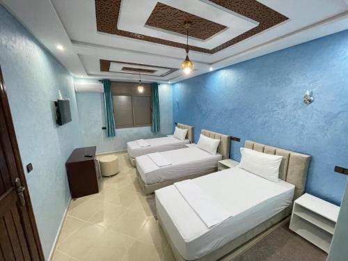 拉希迪耶IGHIZ INN resort的一间设有三张床和蓝色墙壁的房间