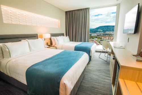 布卡拉曼加Sonesta Hotel Bucaramanga的酒店客房设有两张床和大窗户。