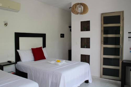 巴卡拉尔Casa Zazil的一间卧室配有两张带白色床单和红色枕头的床。