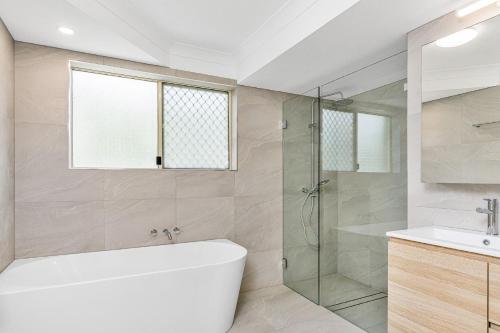 拜伦湾海滩天堂4号公寓的带浴缸和玻璃淋浴间的浴室。