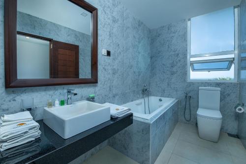 坦加拉Grand Samudra Hotel的一间带水槽、浴缸和镜子的浴室