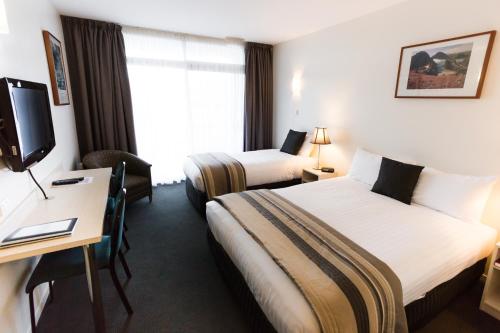 霍巴特海岸线酒店的酒店客房设有两张床、一张桌子和一台电视。
