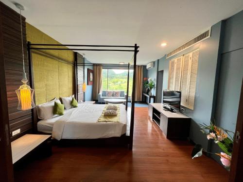 Ban Khanong Phra Taiโรงแรมวิลลา พาราดี的一间卧室配有一张天蓬床和一台电视机