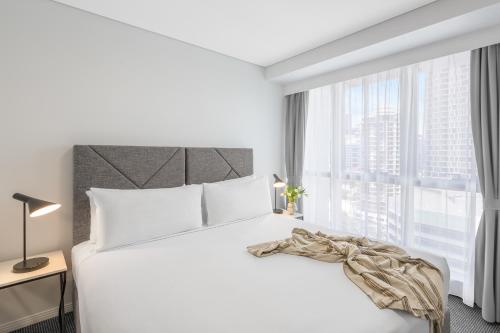布里斯班Meriton Suites Adelaide Street, Brisbane的卧室设有白色的床和大窗户