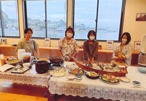 上天草Minshuku Hiro - Vacation STAY 84405v的一群站在餐桌旁的女人,带着食物