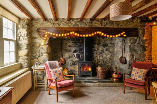 多尔盖罗Finest Retreats - Hope House - Ty Gobaith的客厅设有石制壁炉和两把椅子