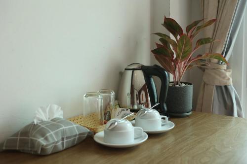 芭东海滩New Forest Patong的一张桌子,上面放着两杯咖啡,还有一株植物