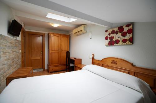 阿维莱斯塞拉芬膳食公寓的卧室配有白色的床和电视。