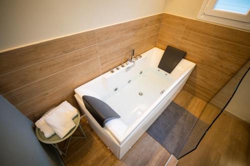 沃洛斯Belajo Central Apartment And Jacuzzi !!的带浴缸的浴室,设有木墙