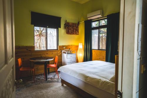 满洲乡Wild East Country House的一间卧室配有一张床、一张桌子和两个窗户