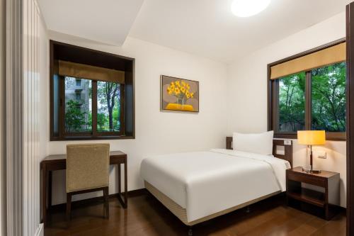 无锡无锡柏雅居东和苑全套房酒店公寓的一间卧室配有一张床、一张桌子和一把椅子