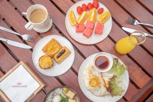泉州泉州滨江皇冠假日酒店的一张桌子,上面有三盘早餐食品和咖啡
